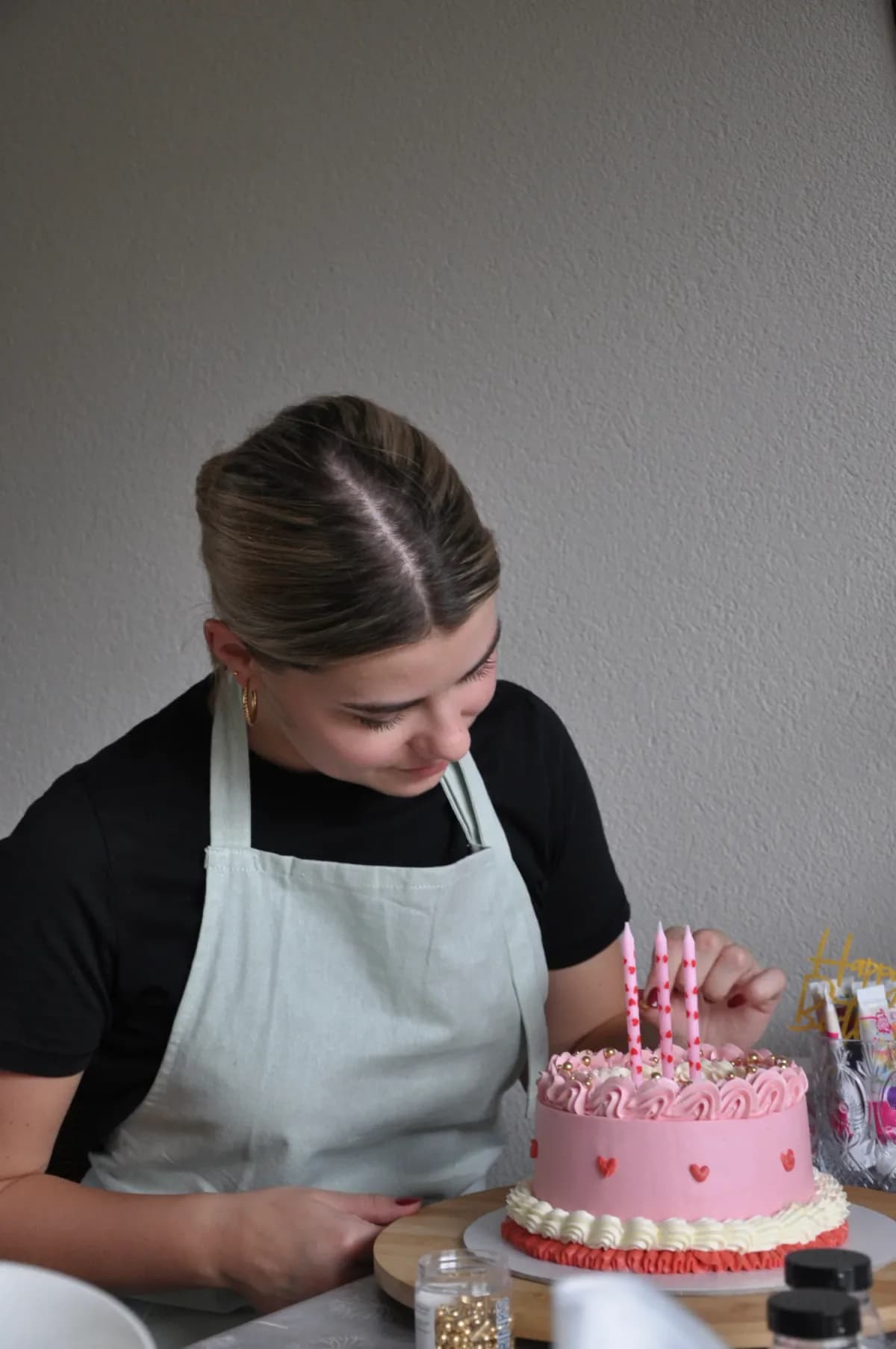 Jasmijn van Sweets by Jasmijn versiert een roze hartjestaart